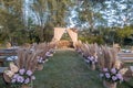 A rustic garden wedding setup, the main aisle lined with baskets with pampas leaves and pastel pink roses. Trees in the background Royalty Free Stock Photo