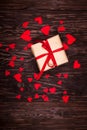 Rustic gift with a red ribbon on wooden background
