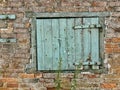 Rustic Green wooden window shutter on a brick farm wall. Atherstone, UK. Royalty Free Stock Photo