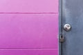 Rustic grey metal door with lock on pink wall