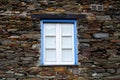 Rustic hand-hewn wood window set into a stone wall built from schist in PiodÃÂ£o, made of shale rocks stack, one of Portugal's