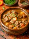 Rustic Homemade Beef Stew with Carrots and Potatoes in Clay Bowl Garnished with Fresh Parsley on Wooden Table Royalty Free Stock Photo