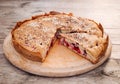 Rustic homemade cherry and cherry plum pie sprinkled with sesame seeds on a round cutting board on an old wooden table Royalty Free Stock Photo