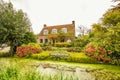 Rustic house with beautiful garden with borders with many flowering plants