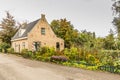 Rustic house with beautiful garden with borders with many flowering plants