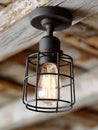 Rustic industrial ceiling light with vintage bulb and wire cage. Royalty Free Stock Photo