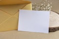 Rustic invitation or greeting card mock up template with golden envelope, blank empty white paper, wood and flowers on Royalty Free Stock Photo