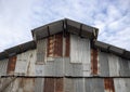 Rustic iron board building wall and roof on sky background. Simple warehouse. Wall and roof made of corrugated iron