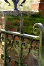 Rustic iron gate in front of a mossy brick wall.