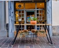 Rustic iron and wood table in front of the door of a bar with pots above and hanging