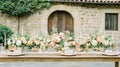 Rustic Italian wedding table setting, peach flowers, stone building Royalty Free Stock Photo