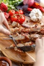 Rustic. Juicy pork is cut with a knife and fork. Appetizing shish kebabs and fresh vegetables on a wooden background.