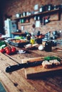 Rustic kitchen setting with fresh vegetables and bread on wooden table Royalty Free Stock Photo