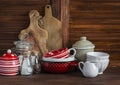 Rustic kitchen still life. Olive cutting board, jar of flour, bowls, pan, enamelled jar, gravy boat. On a dark brown wooden ta Royalty Free Stock Photo