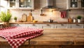 Rustic kitchen tabletop with red and white checkered tablecloth and blurred background of kitchen cabinets and appliances. Royalty Free Stock Photo