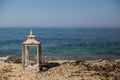Rustic lantern with candle and seashells by the seaside