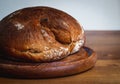 Rustic loaf of fresh bread with bits of flour on a wooden plate