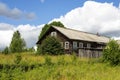 Rustic log old wooden house in village on hill on natural background of sky clouds grass trees Royalty Free Stock Photo