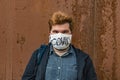 Rustic male portrait in face mask with inscription Covid man looking at camera on rusty decay wall