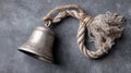 Rustic metal bell with frayed rope on gray concrete surface Royalty Free Stock Photo