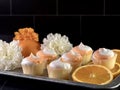 Rustic metal tray filled with fresh orange slices, mini orange creamsicle cupcakes with white and orange frosting and artificial