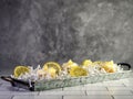 Rustic metal tray with mini swirl lemon cupcakes and lemon slices on top of white paper shreds with a white subway tile counter Royalty Free Stock Photo