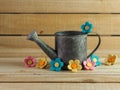 Rustic metal watering can surrounded by felt flowers on a real wood background.  Pink, yellow and blue felt flowers.  Country Royalty Free Stock Photo