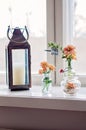 Rustic metallic lantern with a candle and many different glass vases and jugs with beautiful orange gerbera daisy flowers, in Royalty Free Stock Photo