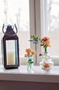 Rustic metallic lantern with a candle and many different glass vases and jugs with beautiful orange gerbera daisy flowers, in Royalty Free Stock Photo