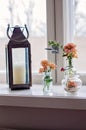 Rustic metallic lantern with a candle and many different glass vases and jugs with beautiful orange gerbera daisy flowers, in Royalty Free Stock Photo