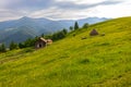 Rustic mountain cabin and haystack in green meadow. Traditional wooden cabin and haystack on a hillside meadow, surrounded by Royalty Free Stock Photo