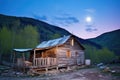 rustic mountain shack under a glowing moon