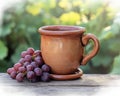 A rustic mug containing grape drink is positioned on a wooden table, surrounded by fresh grapes and vines Royalty Free Stock Photo