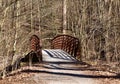 Rustic old metal and wooden bridge over a creek in a forest. Royalty Free Stock Photo