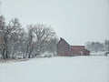 Rustic old red barn standing strong in a Nebraska winter storm with snow and ice. Royalty Free Stock Photo