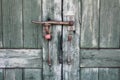 Rustic old wooden doors with rusted metal handles and strong latch locked with small padlock