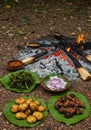 Outdoor campfire cooking with various traditional dishes served on banana leaves Royalty Free Stock Photo