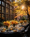 Rustic outdoor table setting with candles, vase of flowers and yellow leaves for a warm and inviting feel