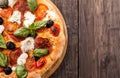 Rustic pizza with salami, mozzarella, olives and basil on wooden Royalty Free Stock Photo
