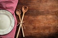 Empty plate, kitchen utensils and red tablecloth on wooden table, top view, copy space Royalty Free Stock Photo