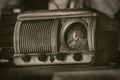 Old vintage radio receiver of the last century with rustic clock build in, on shelf - front view, sepia style photography