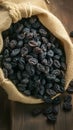 Rustic raisin display Black raisins in burlap bag on wooden table