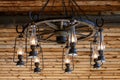 Rustic ranch chandelier made from wood wagon wheel, iron horseshoes, and lanterns, hanging from aged wood ceiling