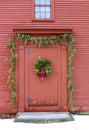 Rustic red barn with boughs of fir trees decorating front entrance and pretty wreath on door Royalty Free Stock Photo