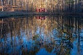 Rustic red boathouse on the edge of a tranquil pond with its reflection in the peaceful waters Royalty Free Stock Photo