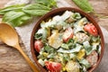 Rustic salad of boiled eggs, potatoes, tomatoes and fresh herbs seasoned with yogurt close-up in a bowl. Horizontal top view