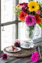 A rustic scene of tea and a scone served with jam with pretty flowers in behind.