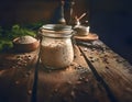 A rustic setting featuring a jar of sourdough starter and various seeds on a wooden table. Healthy fermentation process.