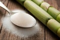 Rustic setup with granulated sugar spoon and sugarcane on wooden surface. Royalty Free Stock Photo