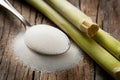 Rustic setup with granulated sugar spoon and sugarcane on wooden surface. Royalty Free Stock Photo
